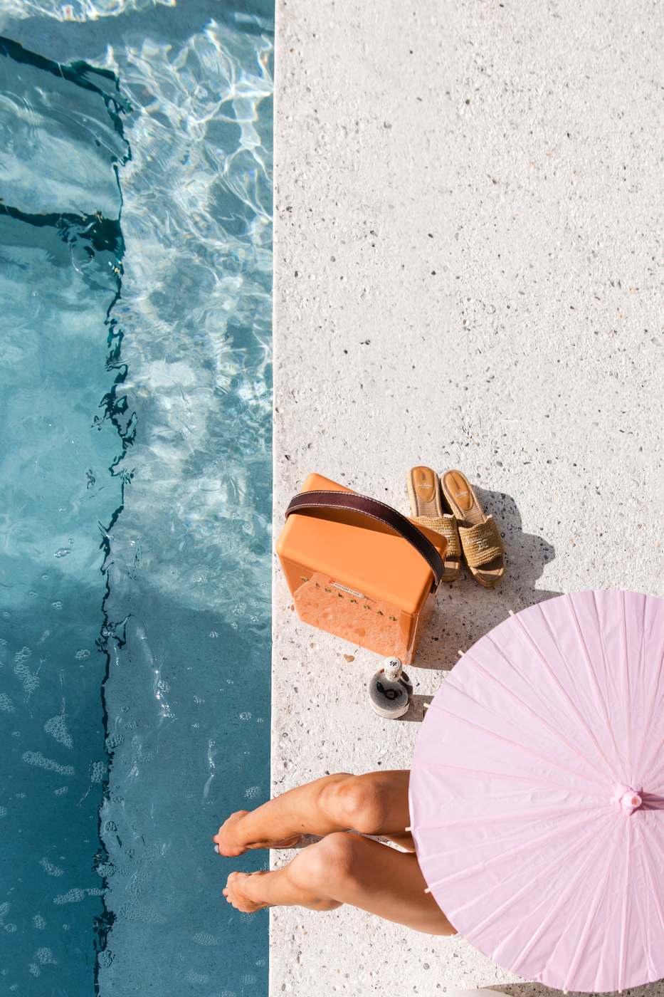 A glimpse from Issue 03 — overhead at the pool's edge, the tile line, a pink parasol and an orange cooler on the deck.
