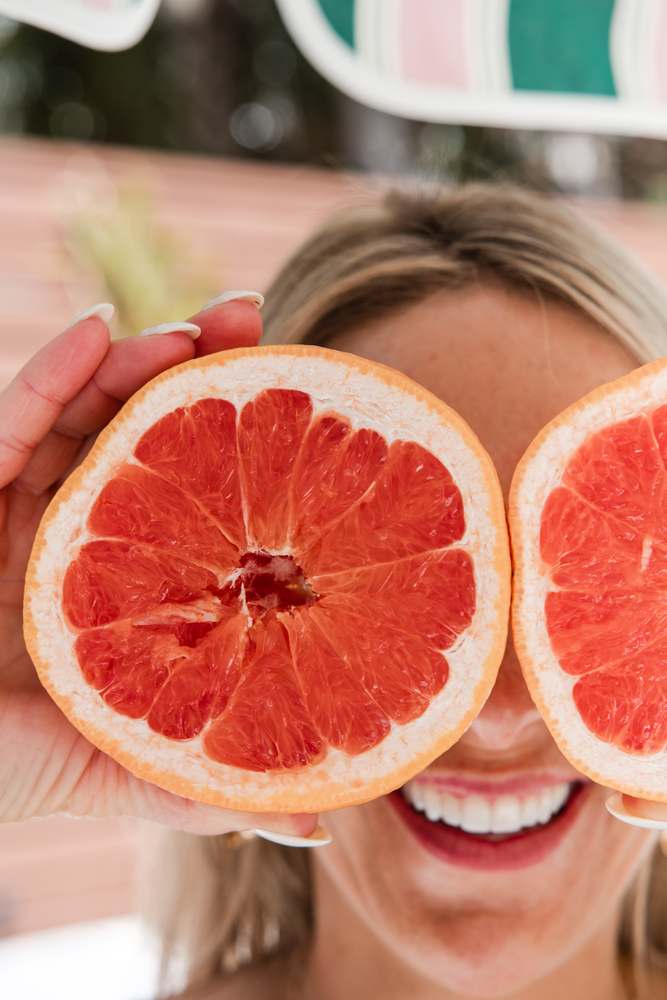 Laughing behind two halves of a grapefruit held up over the eyes.