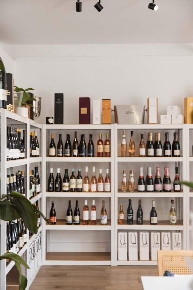 The full shelf wall at Sarasota Wine Co. — sparkling, rosé and small-producer whites from floor to ceiling.
