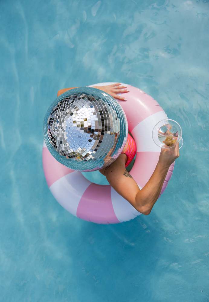 Overhead: floating in the pink and white ring in the middle of the pool, the mirror ball resting on the water alongside.